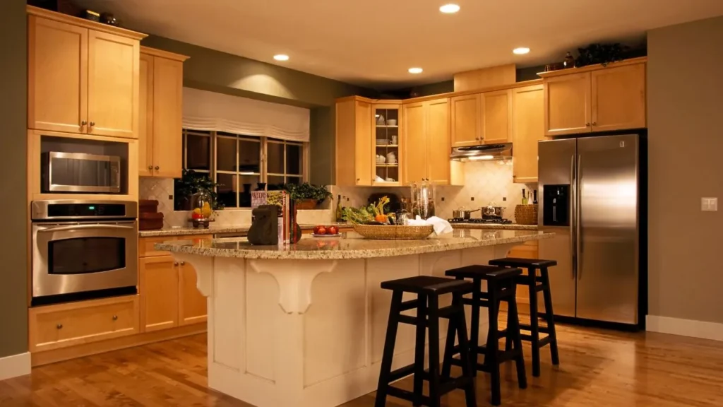 A well-equipped culinary space with warm maple cabinetry and a curved granite island, offering prep space worthy of a cutthroat kitchen competition.