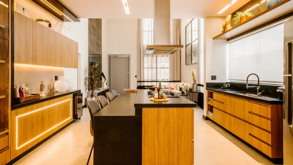 High-ceiling contemporary home showcasing a modern kitchen design and island layout with warm LED under-cabinet lighting and sleek wood finishes.