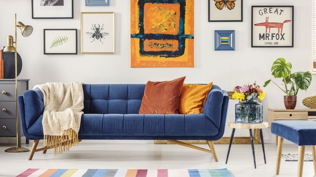 Eclectic living room with a navy blue velvet sofa, colorful gallery wall art, and a striped rug