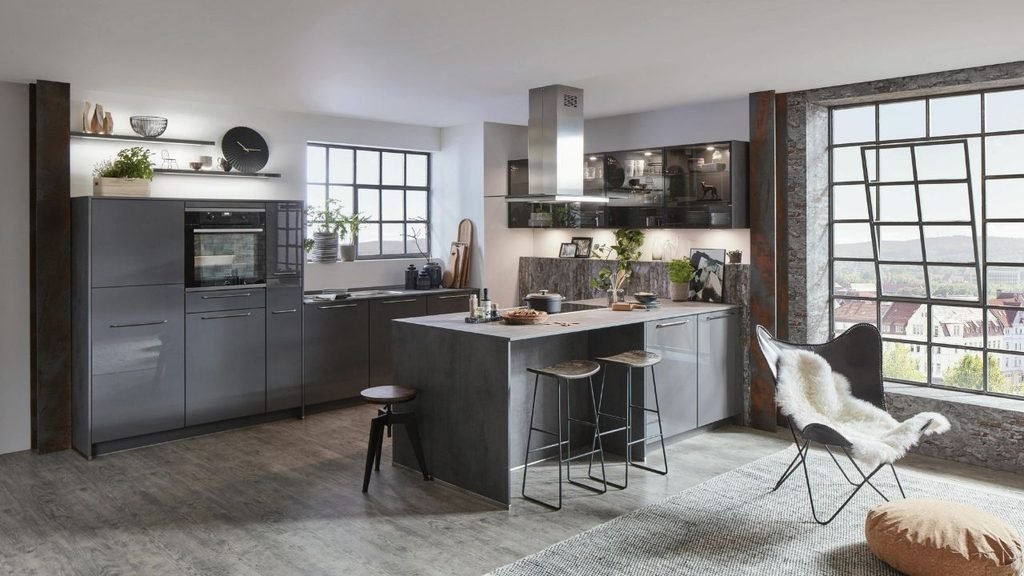 Industrial-style loft kitchen with glossy gray cabinets, a stone-topped island, three bar stools, and large steel-framed windows