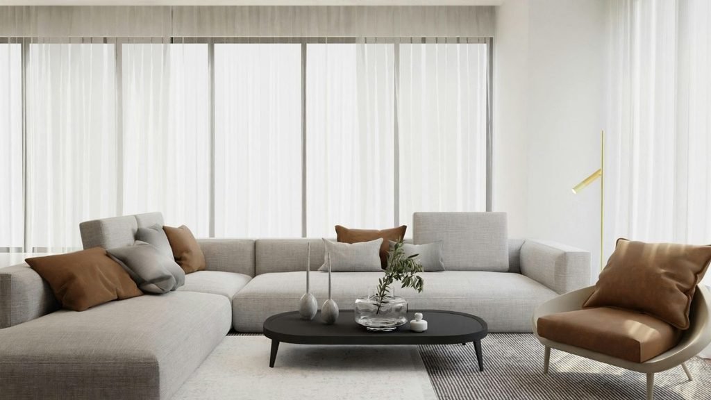 Modern minimalist living room with a gray L-shaped sectional sofa, black oval coffee table, and sheer curtains along floor-to-ceiling windows
