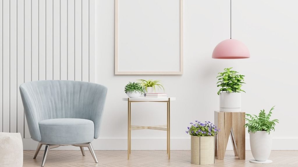 Modern living room corner with a light blue velvet armchair, gold side table, pink dome pendant light, and potted plants