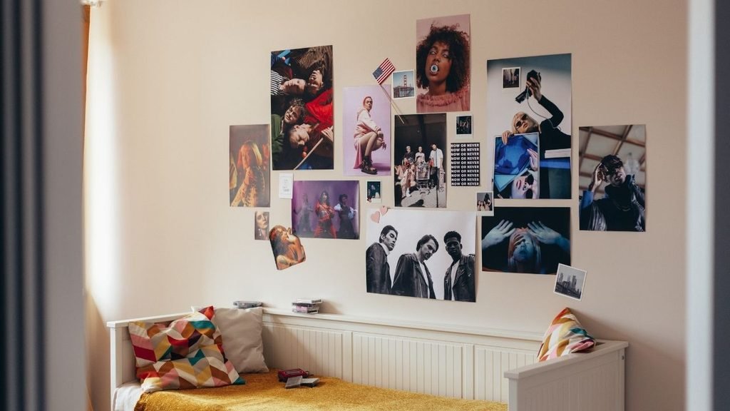 Teen bedroom with a large photo collage of magazine cutouts and portraits above a daybed with colorful geometric pillows