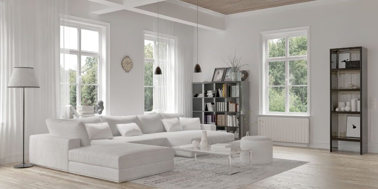 Elegant gray living room with wainscoting wall paneling, framed botanical prints, twin round coffee tables, and herringbone wood flooring