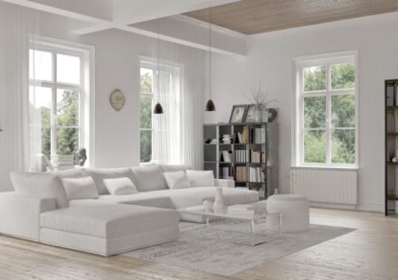 Elegant gray living room with wainscoting wall paneling, framed botanical prints, twin round coffee tables, and herringbone wood flooring