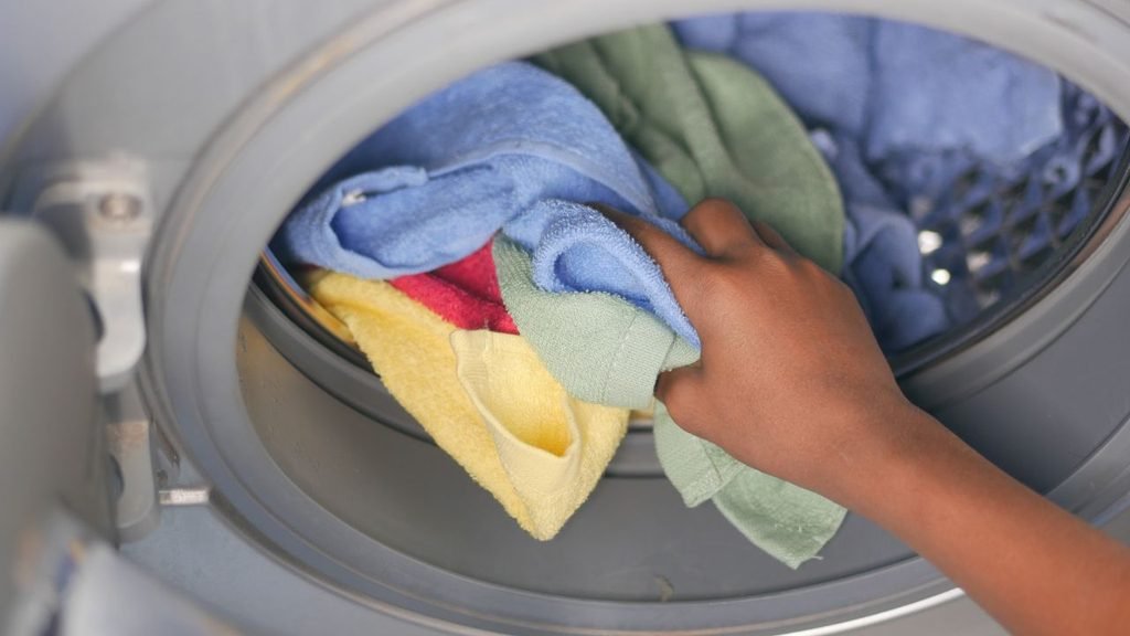 Close-up of a hand pulling colorful towels out of a clothes dryer drum