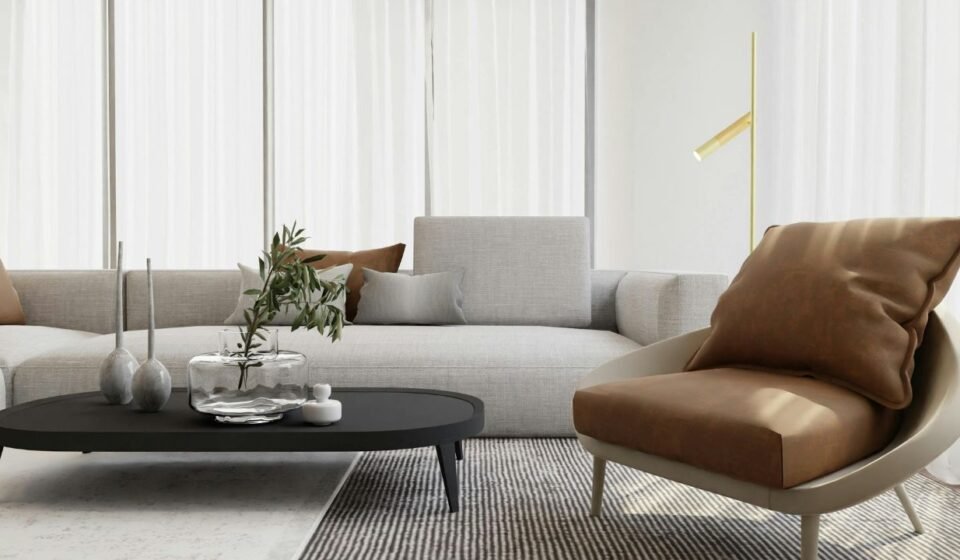 Living room with sheer curtains, a glass vase on a black coffee table, and a tan leather accent chair beside a slim gold floor lamp