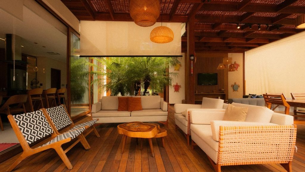 Open-plan living and dining area with wood-slat ceiling, hanging rattan pendant lights, and indoor palm tree drawing the eye upward