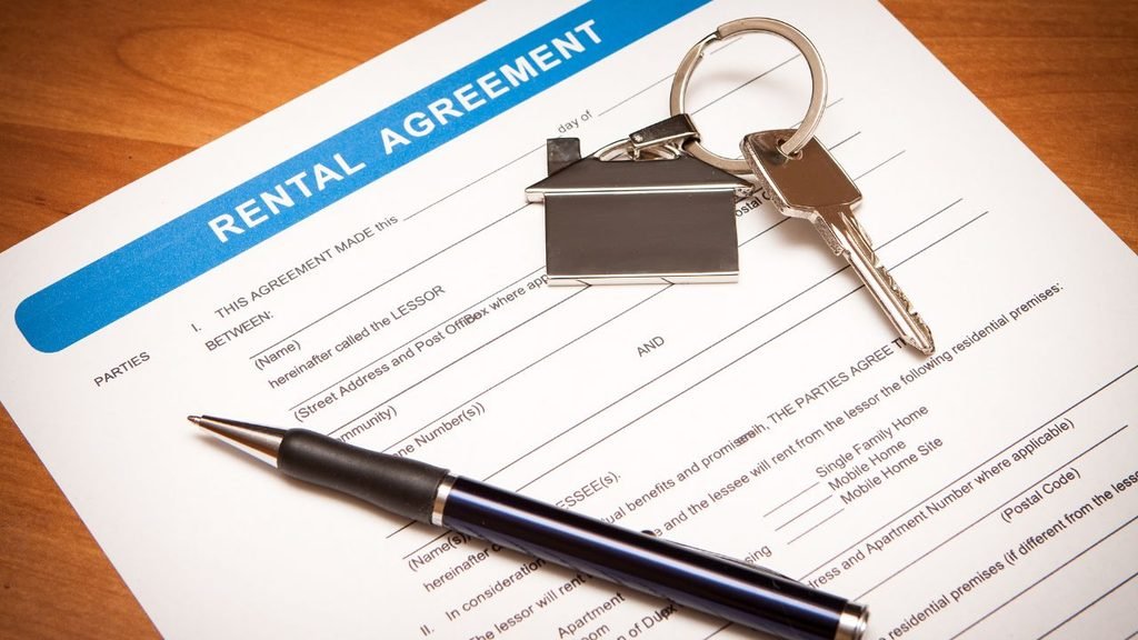 Close-up of a printed residential rental agreement form with a silver pen and a set of house keys resting on top.