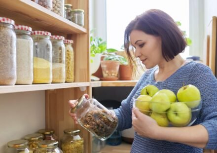 Clear stackable bins organized neatly inside a small kitchen pantry shelf