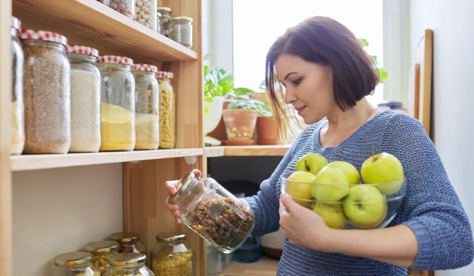 Clear stackable bins organized neatly inside a small kitchen pantry shelf