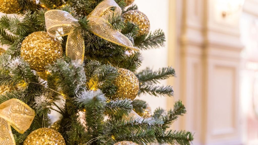 Glamorous Christmas tree with gold glitter baubles and sheer gold ribbon, an elegant christmas tree design idea for parties