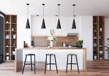 Four black cone pendant lights with gold interiors above a wood-and-white island in a modern kitchen