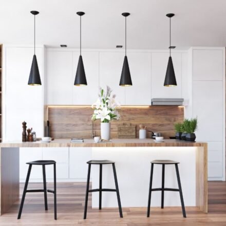 Four black cone pendant lights with gold interiors above a wood-and-white island in a modern kitchen