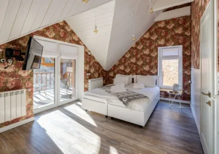 Cozy attic bedroom with vintage floral wallpaper for wall designs and bright natural lighting.