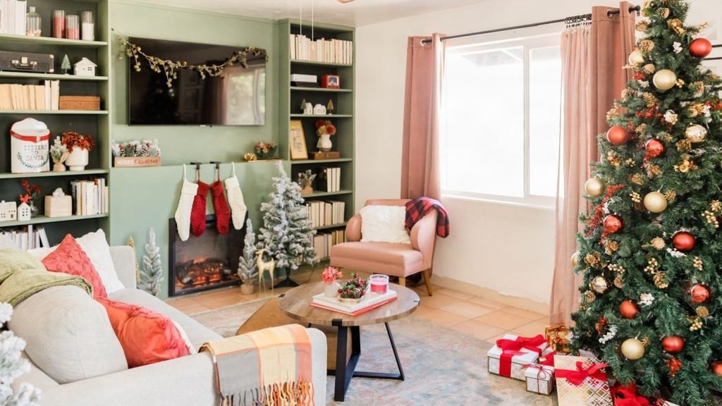 Living room Christmas decor inspiration with green built-in shelves, hanging stockings, flocked mini trees and a red and gold tree