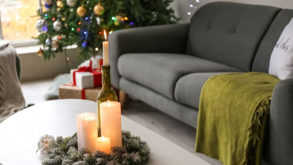 Holiday living room centerpiece idea with white pillar candles and a wine bottle candle holder on a frosted mini wreath