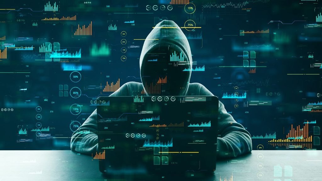 Hooded figure working at a laptop surrounded by glowing digital charts and graphs