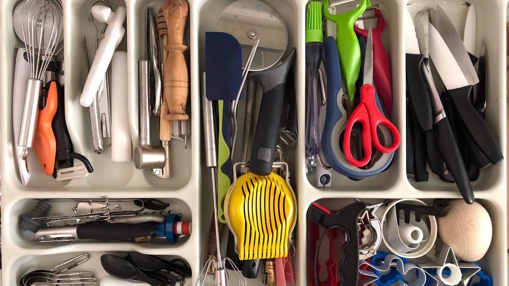 Kitchen drawer organization idea with a gray cutlery tray holding stainless steel spoons inside a white kitchen cabinet drawer