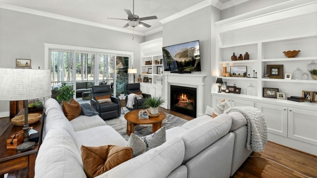 Living room with a lit fireplace, white built-in shelves, a light gray sectional and a chunky knit throw.