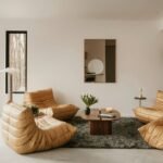 Minimalist cosy interior living room with a beige sectional sofa, floor-to-ceiling windows, built-in bookshelves and green plants
