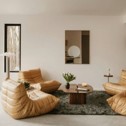 Minimalist cosy interior living room with a beige sectional sofa, floor-to-ceiling windows, built-in bookshelves and green plants