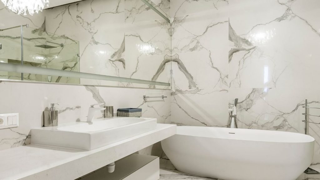 Modern bathroom remodel ideas: white marble-look tile, oval freestanding tub and a floating vanity with a vessel sink
