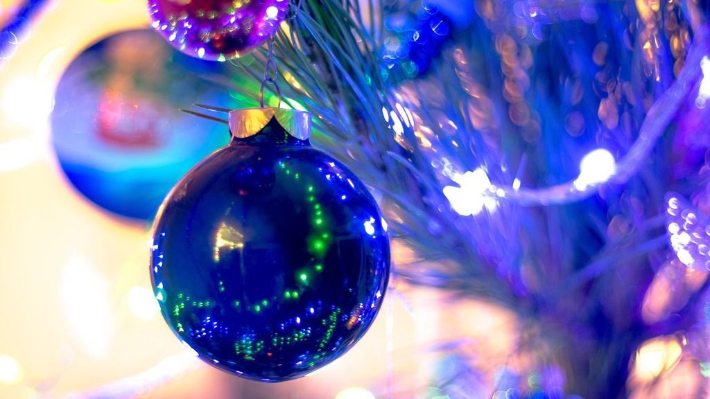 Glossy blue glass bauble reflecting colorful lights, a modern christmas tree design idea with a cool-toned color scheme