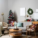 Neutral living room with rattan chairs, brass lamps, green wrapped gifts and a slim tree with red ribbons and silver bows