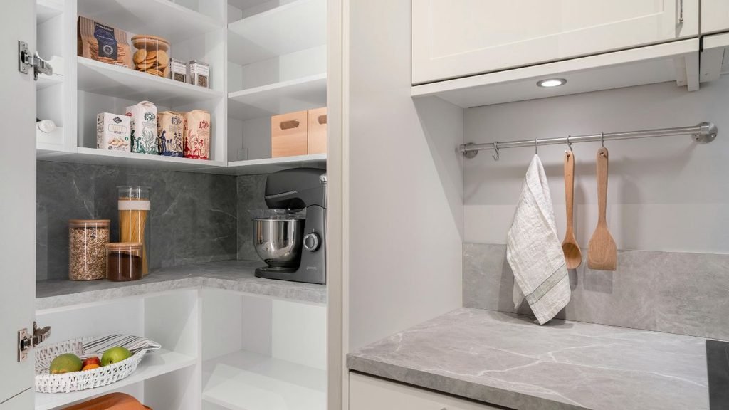Over-the-door wire rack holding bottles of oil and spices in a compact pantry.