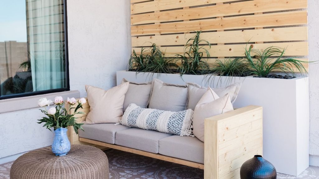 Modern porch with a DIY wood-frame sofa, neutral cushions, a built-in planter and a slatted wood wall, a fresh look for 2027