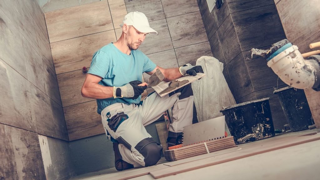 Tile installer spreading thinset on wood-look wall tile, a rustic bathroom remodel idea