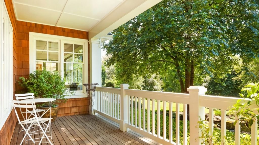 Compact wood-floor porch with a white folding bistro table and chairs beside a white railing, a small space idea that still feels open