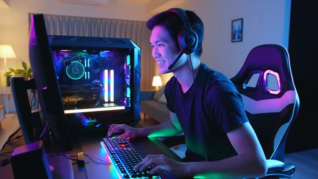 Smiling gamer with a headset at a glass-panel PC and RGB keyboard, one of the best small room gaming setup ideas for a living space