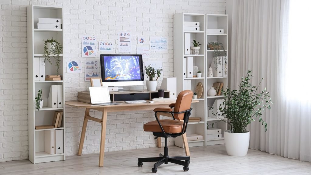 Minimalist white home office with a wooden desk, monitor and shelves, easily adapted into a small room gaming setup for PS5