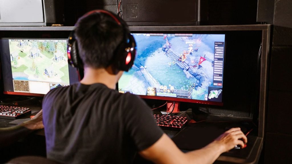 Player at a dual-screen desk in a tight space, a small room gaming setup that upgrades from an Xbox One to a PC