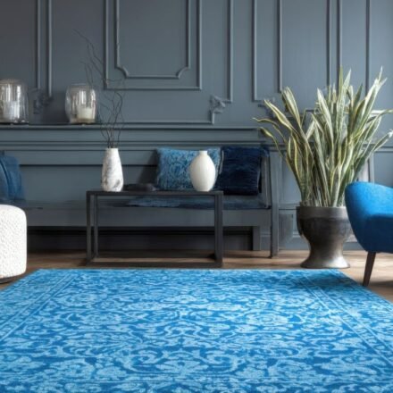 Dark gray-blue wainscoting panels behind a bench, with a blue armchair, patterned blue rug and potted snake plants